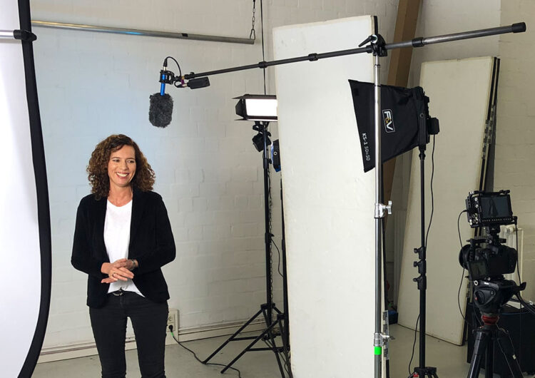 Ein moderner Imagefilm Dreh im Studio. Eine Frau steht vor der Kamera und lächelt.