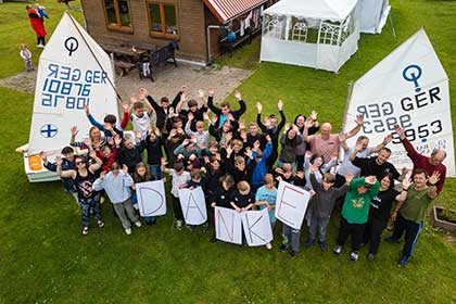 Etwa 50 Kinder und Jugendliche winken fröhlich in die Kamera. Gruppenfoto beim Segelcamp Lychen 2025. Standbild aus einem Eventfilm von Brandenburg Film Foto.